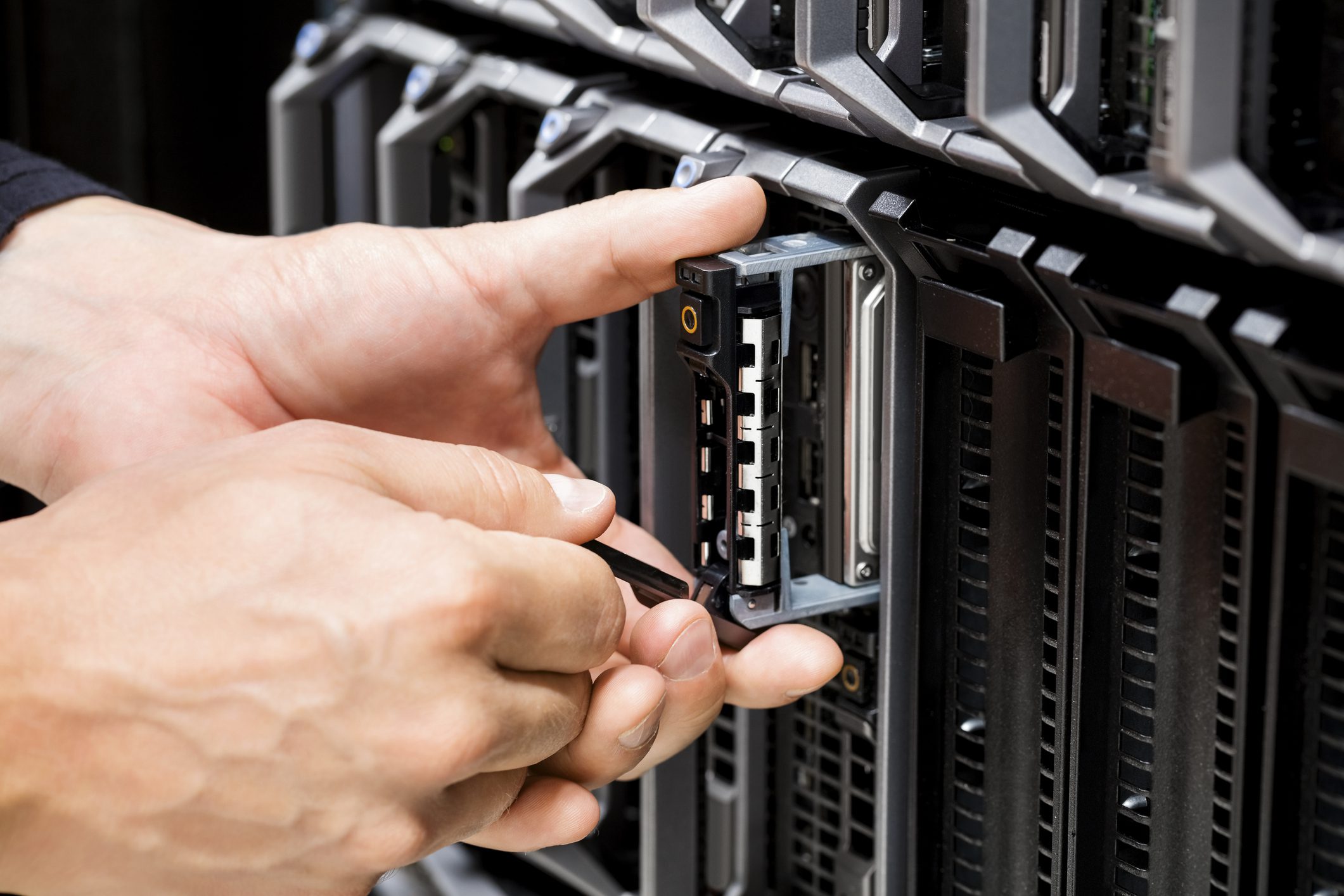 Hands installing hard drive in server.
